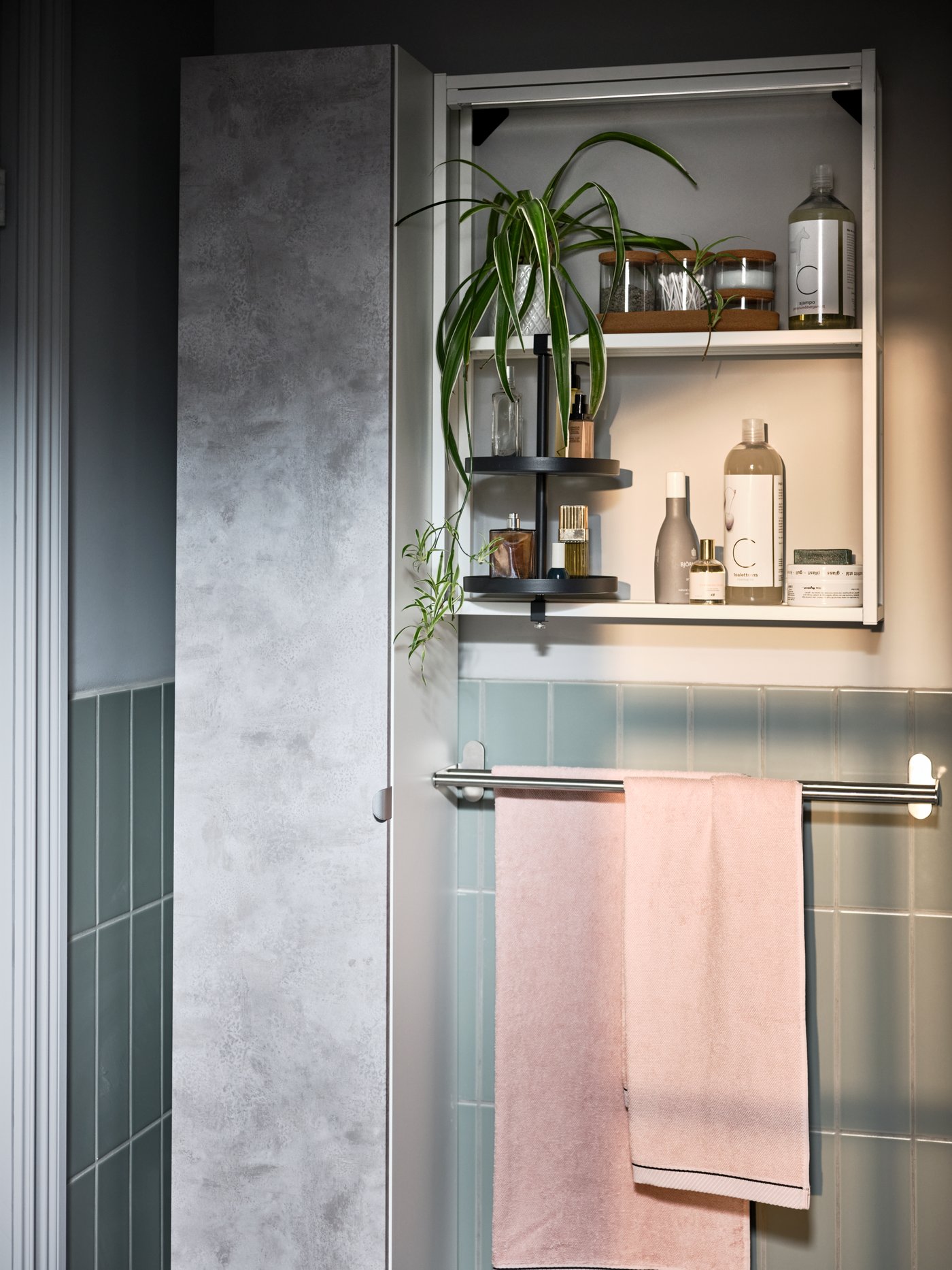 قسم من حمام مكسو بالبلاط مع خزانة مرتفعة ENHET بتأثير الخرسانة ومناشف يد ذات لون وردي فاتح على سكة تعليق مناشف BROGRUND.