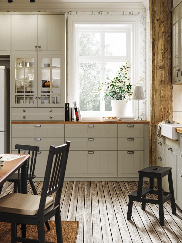 Ein Kind steht auf einem MÄSTERBY Tritthocker, auf dem Boden liegen um den Hocker herum Zwiebelschalen.