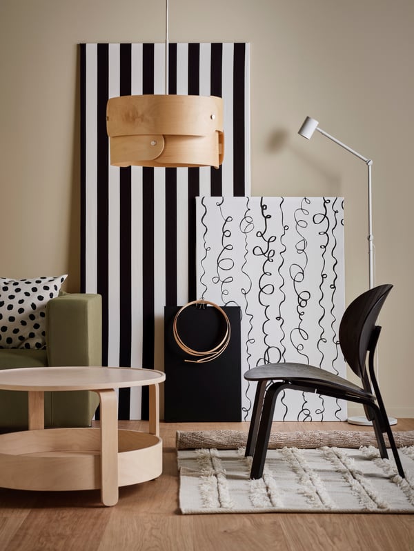 A black FRÖSET easy chair on a natural PEDERSBORG rug, next to a yellow-green KLIPPAN sofa and a birch BORGEBY coffee table.