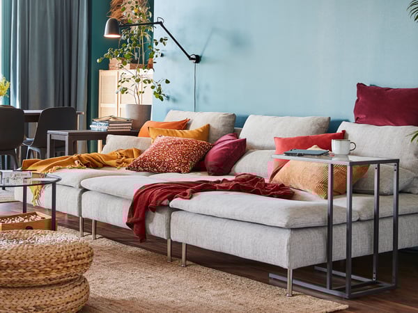A SKURUP work/wall lamp is mounted on the wall above three SÖDERHAMN chaise longues in a colourful living room.