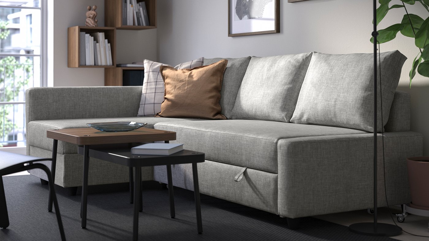 Grå FRIHETEN bäddsoffa med schäslong i ett hemtrevligt vardagsrum med träbord.