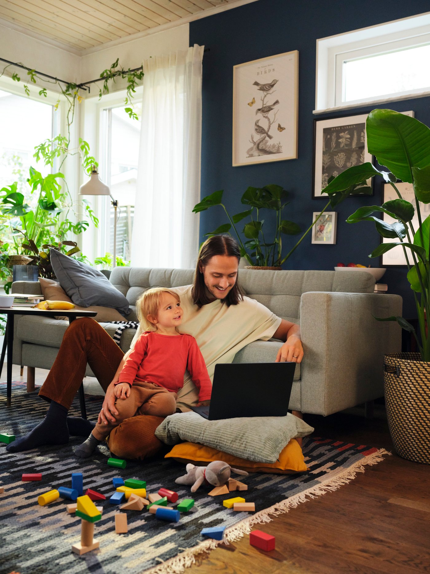 A man at home using the kitchen planner whilst his child plays toys