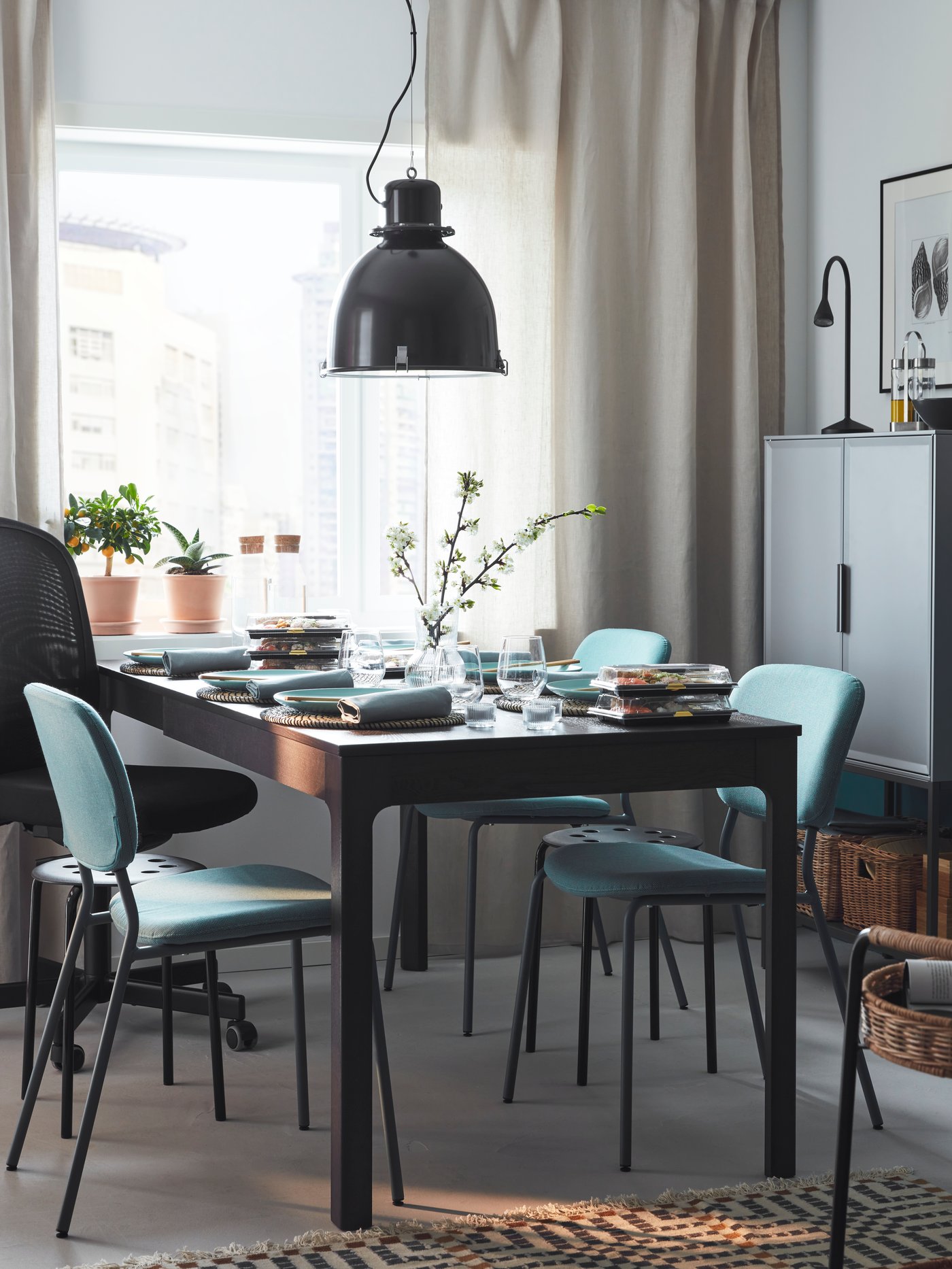 Una mesa EKEDALEN marrón extendida para cenar para seis personas, con una combinación de sillas y taburetes alrededor, junto a una ventana soleada.