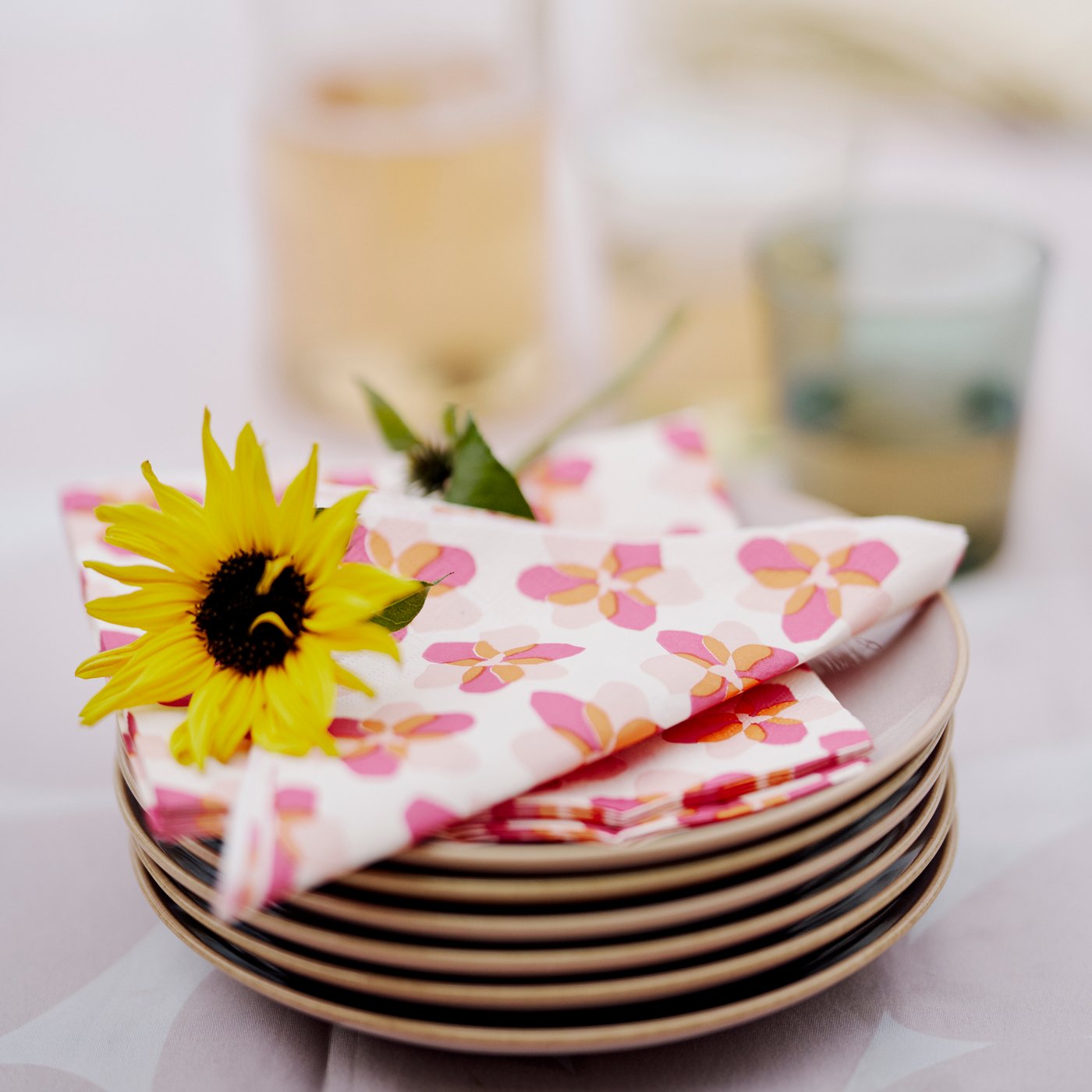 TOFSAND paper napkins in pink, orange and white together with a yellow flower on top, add a vibrant feel to an outdoor table.