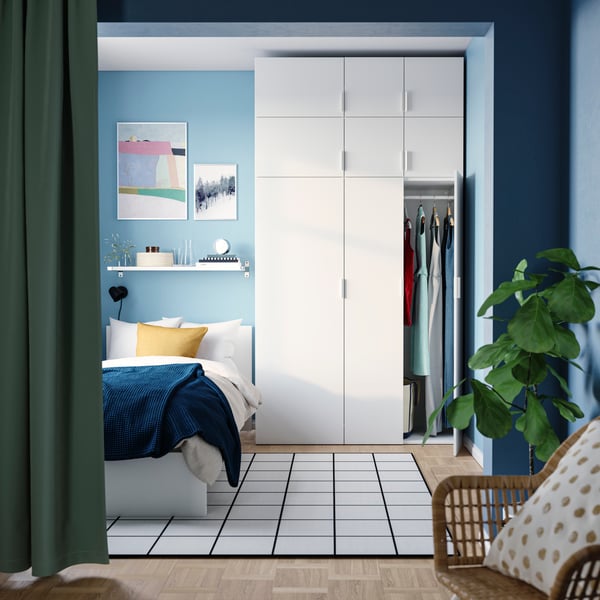 Camera da letto, dove accanto al letto c'è un guardaroba PLATSA bianco con 9 ante che poggia su una parete colorata d'azzurro.