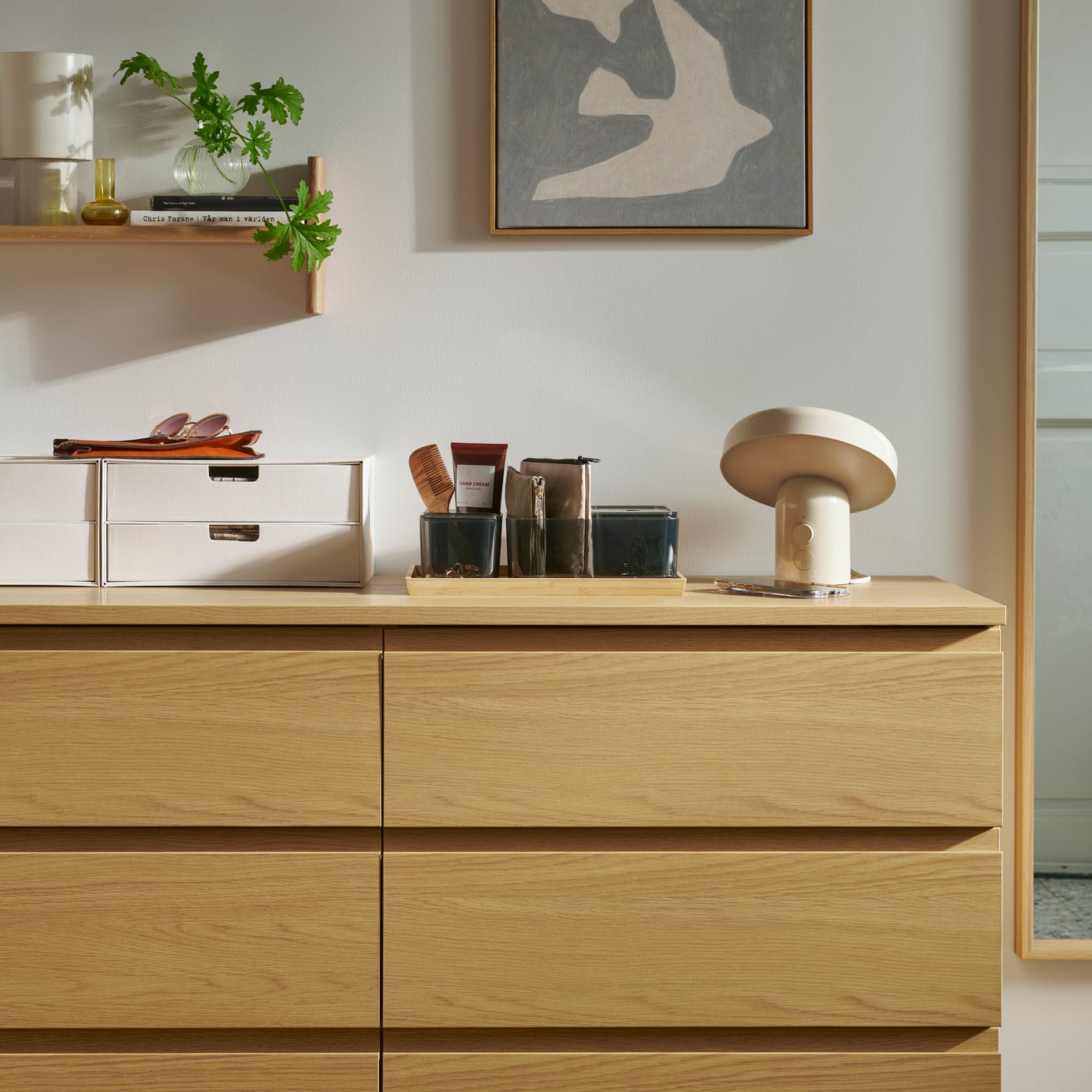 An oak effect STORKLINTA chest of 6 drawers with FJÄDERHARV mini chest of 2 drawers on top and BLODFLÄDER picture on the wall.