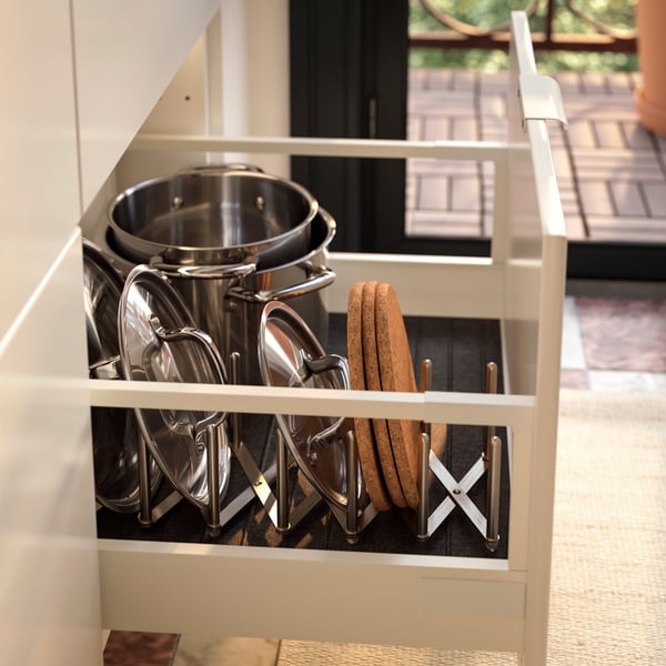 A spacious kitchen drawer features a polished stainless steel pot, pot lids, and neatly arranged wooden cutting boards.