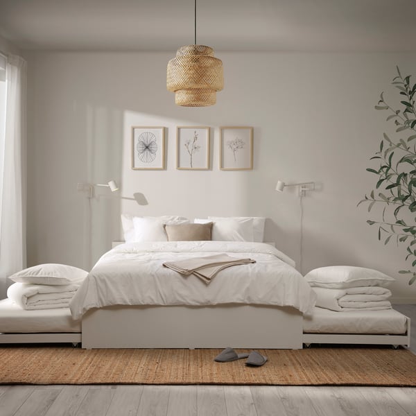 A bedroom with a white VIHALS bed frame and white and beige bedding. A SINNERLIG ceiling lamp hangs from the ceiling.