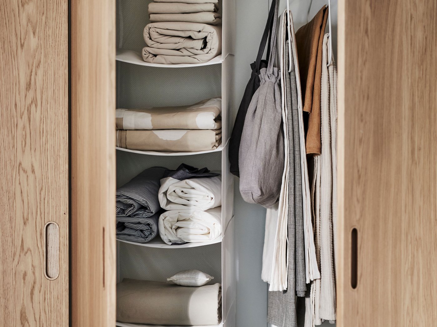 دولاب ملابس PAX / TONSTAD من قشرة خشب البلوط/الأبيض بأبواب مفتوحة تُظهر وحدة تخزين SKUBB باللون الأبيض معلقة وتحتوي على 6 حجيرات بالداخل.