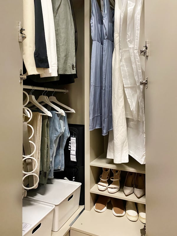 Een open PAX kledingkast met georganiseeerde schoenen, hangers en bakken 