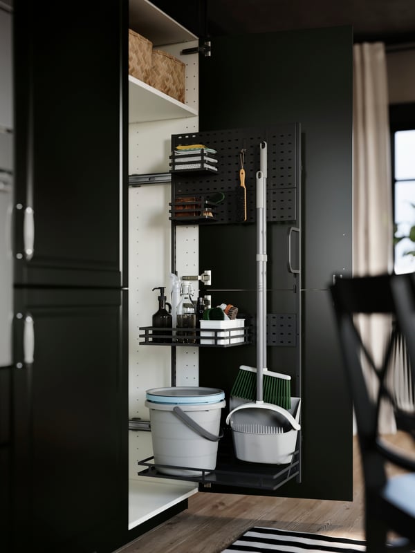 A kitchen cabinet has an open door with an UTRUSTA cleaning interior, with adjustable wire shelves with cleaning supplies.