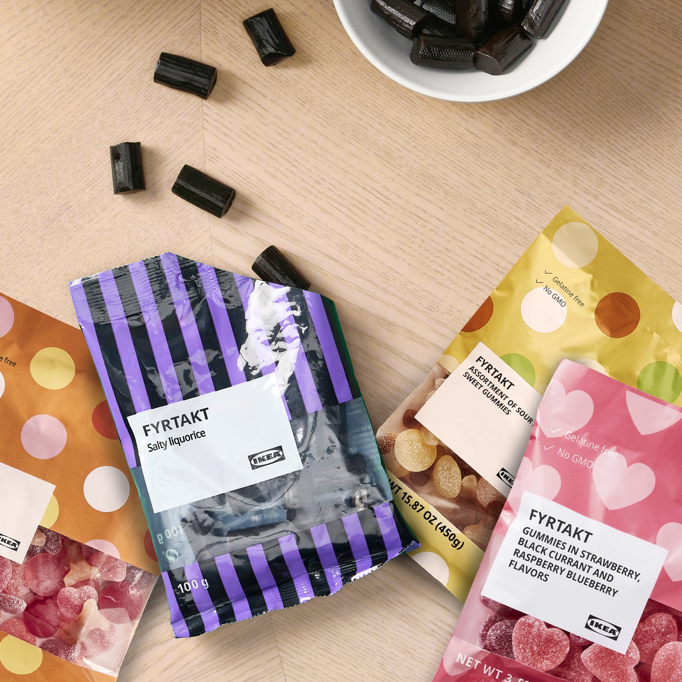 Kolorowe opakowania cukierków IKEA FYRTÅKT na drewnianym stole.