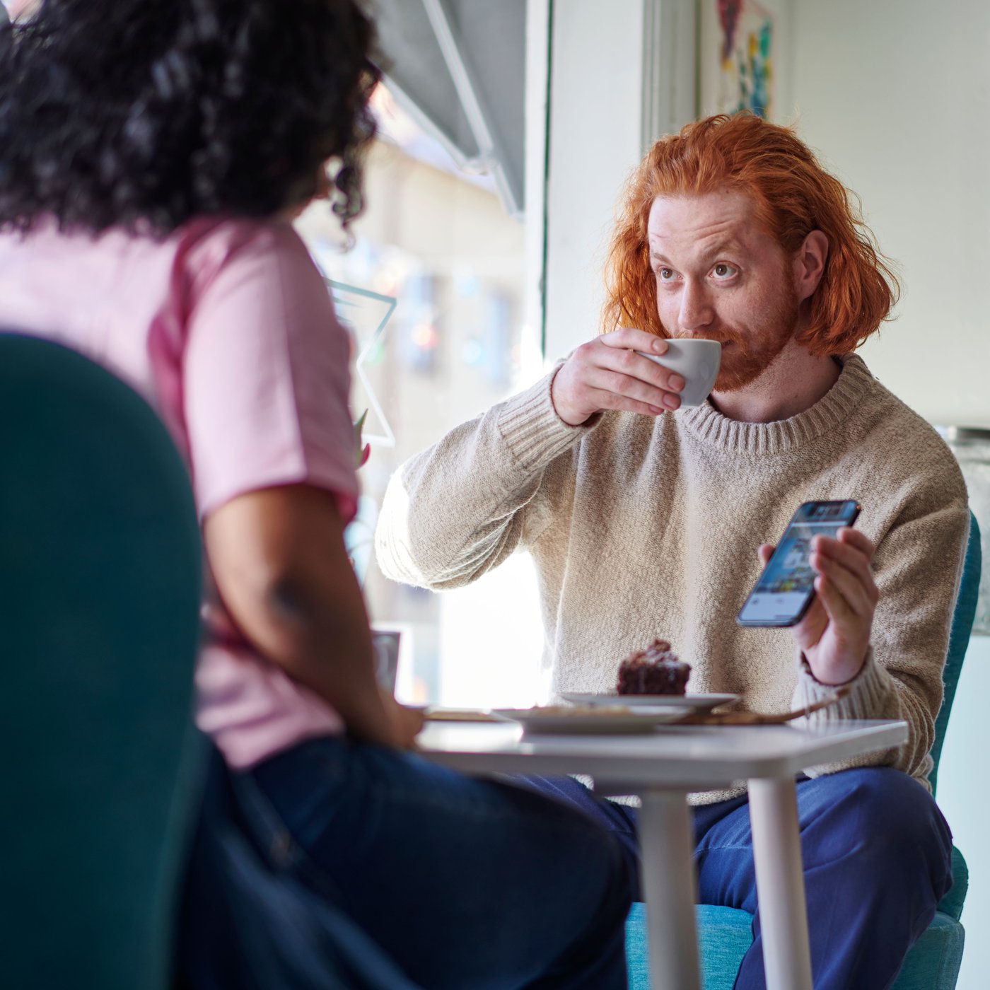 Muž, co pije espresso a ukazuje ženě něco v aplikaci IKEA.