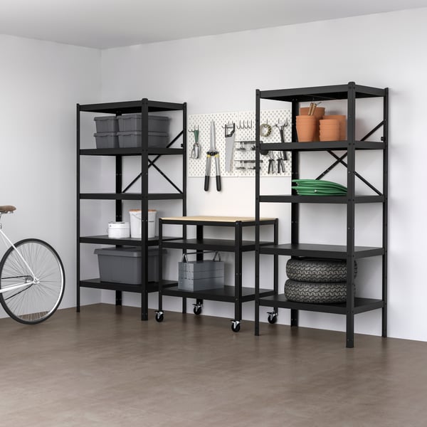 Ein schwarzes Regal mit viel Platz steht vor einer weißen Wand.