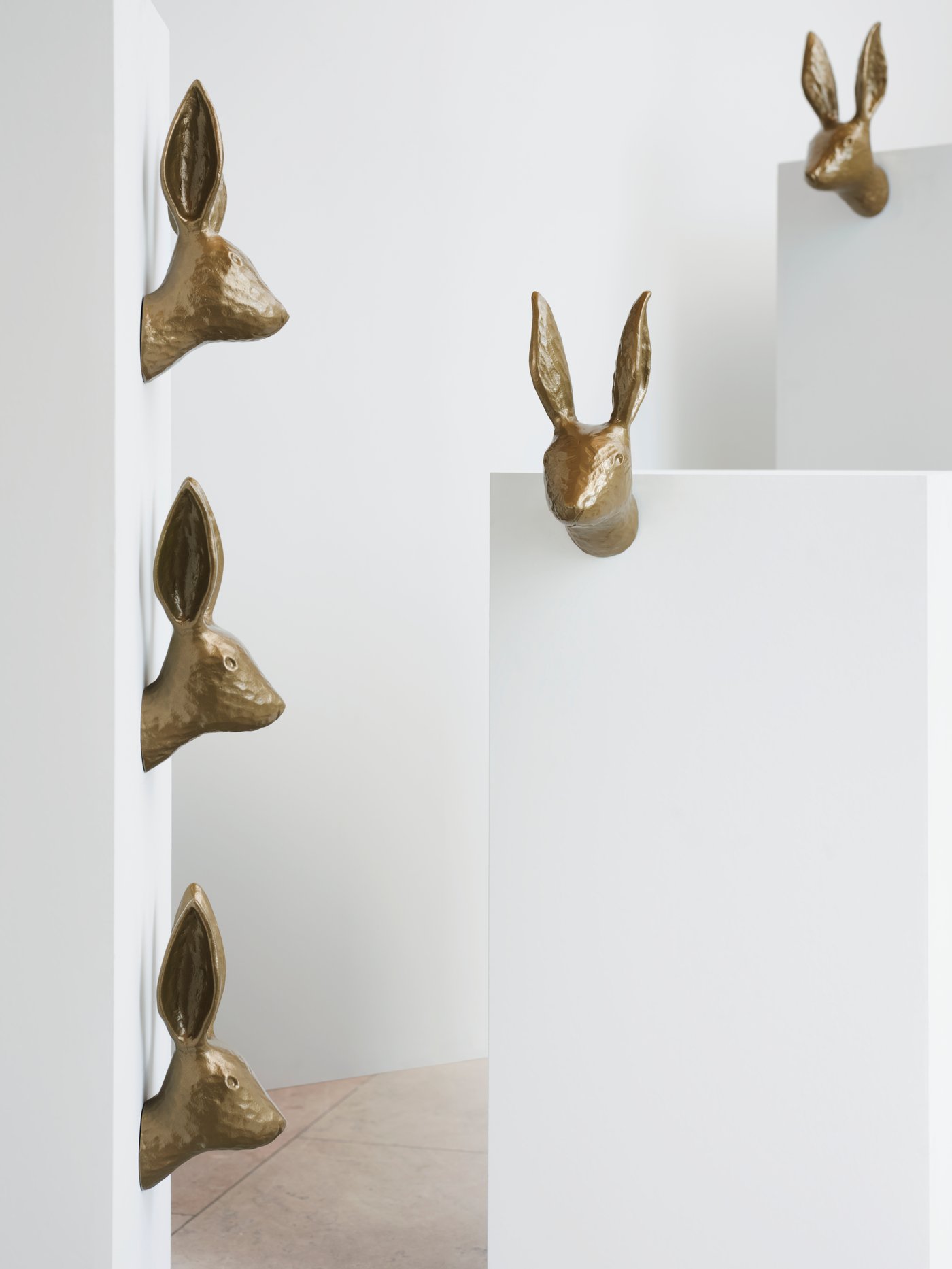 Five HÄGGMISPEL wall decorations featuring brass-coloured rabbits with tall, pointy ears are mounted onto white boxes.