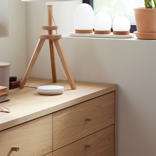 A close-up of the top corner of TONSTAD chest of six drawers in oak veneer, standing in a corner below a window.