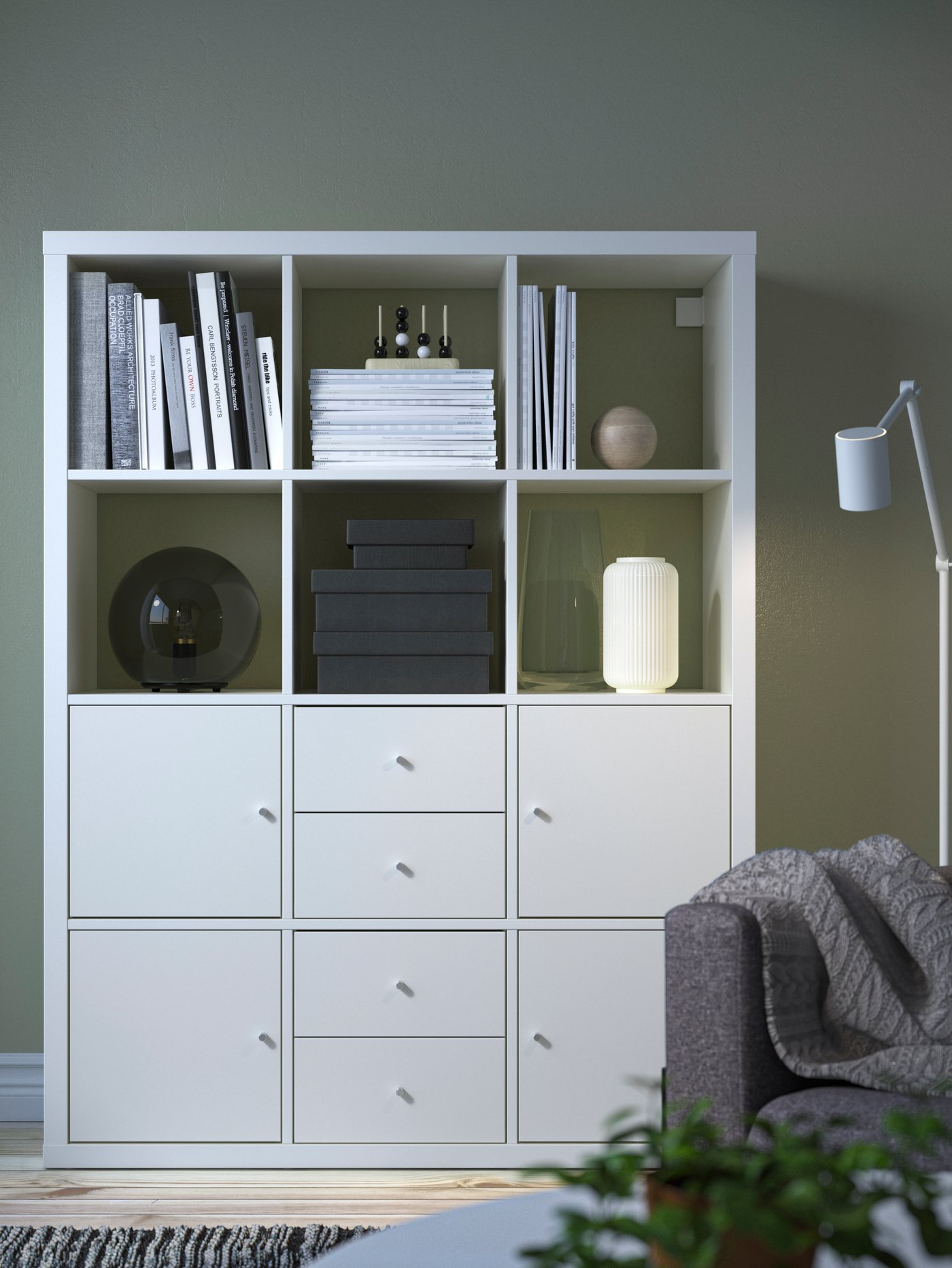 Grå vägg med en vit KALLAX hylla med 12 fack varav den nedersta halvan består av skåp och lådor.