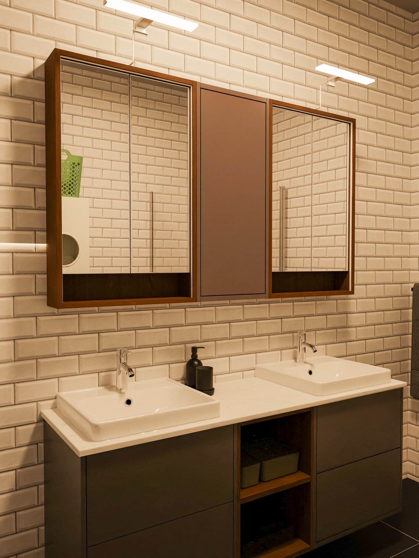 Waschtisch mit zwei Waschbecken und Spiegeln in Nussbaum und grau mit Metrofliesen an der Wand.