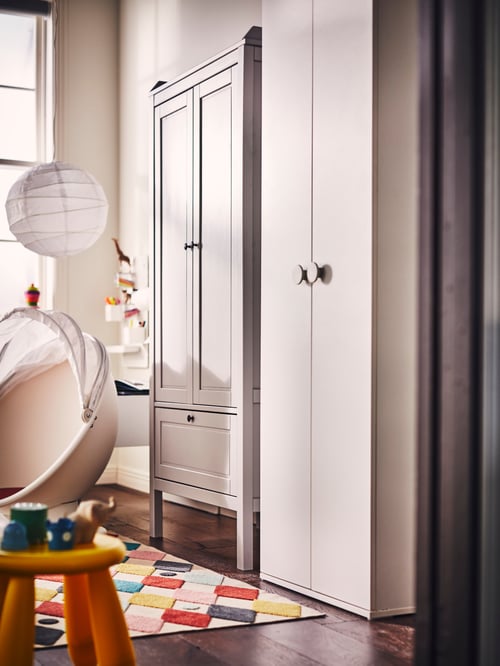 Kinderzimmer mit einem SUNDVIK und einem GODISHUS Kleiderschrank, einem IKEA PS LÖMSK Drehsessel und einem REGOLIT Hängeleuchtenschirm.