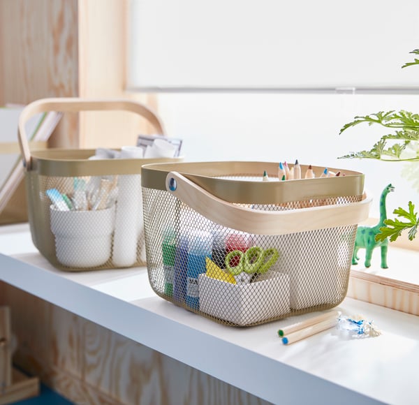 On a window sill are two RISATORP baskets filled with trinkets and clutter.