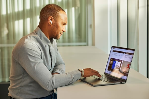 A person video calling on a laptop placed on four white BROR tables put together in the design office of a fashion company