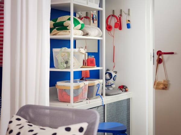 A small Scandi-style hallway with a white PLATSA open wardrobe holding white baskets and folded clothes on its shelves.