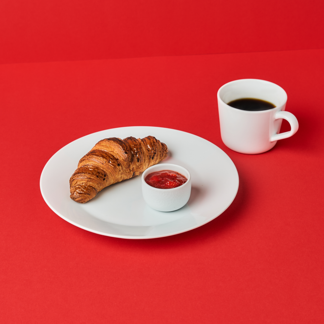 IKEA breakfast with a butter croissant and jam on a white plate.