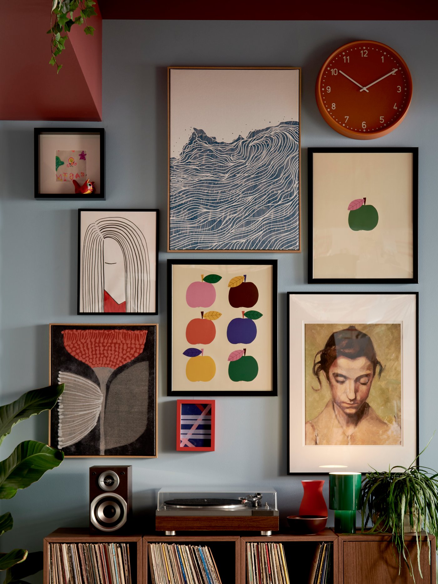 A living room wall adorned with various colourful artworks, featuring BLODFLÄDER pictures in blue, red, and green hues.