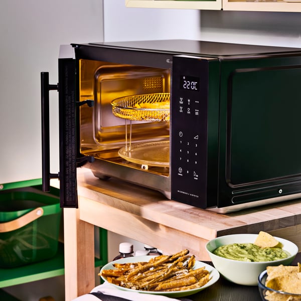 Four à micro-ondes GÅTEBO noir autoportant avec fonction friteuse dans une cuisine d'étudiant.