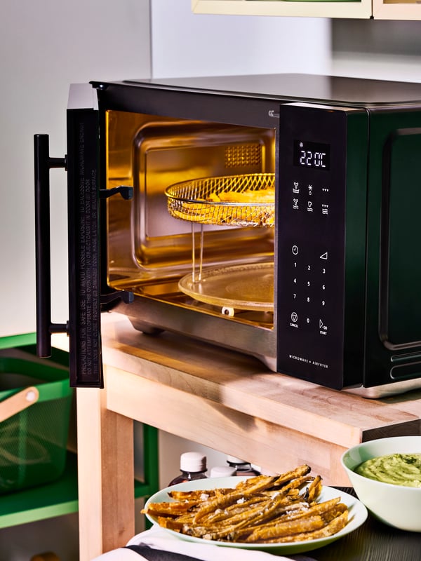 Four à micro-ondes GÅTEBO noir autoportant avec fonction friteuse dans une cuisine d'étudiant.