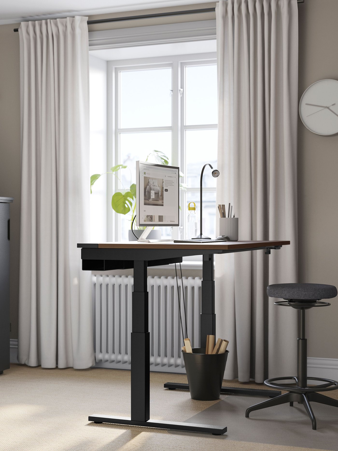 Ein elektrischer Schreibtisch MITTZON Sitz/Steh in Walnussfurnier/Schwarz im Homeoffice.