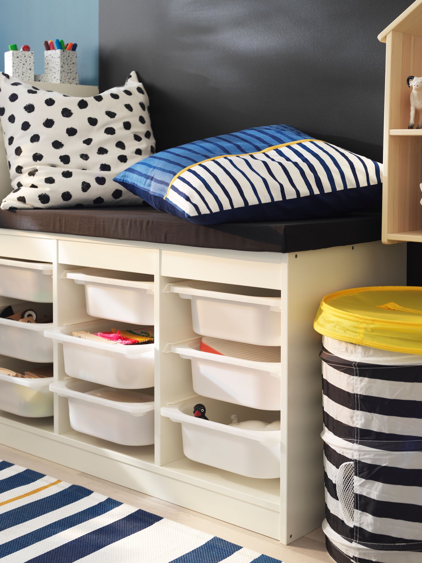 A TROFAST frame is used as a sitting area, with cushions placed on top of it. The frame is filled with TROFAST boxes with miscellaneous items.