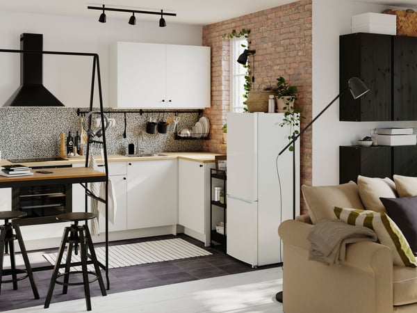 Een kleine open keuken met modules uit de KNOXHULT serie. Aan de ene kant staat een HÅVERUD tafel met opbergladder.