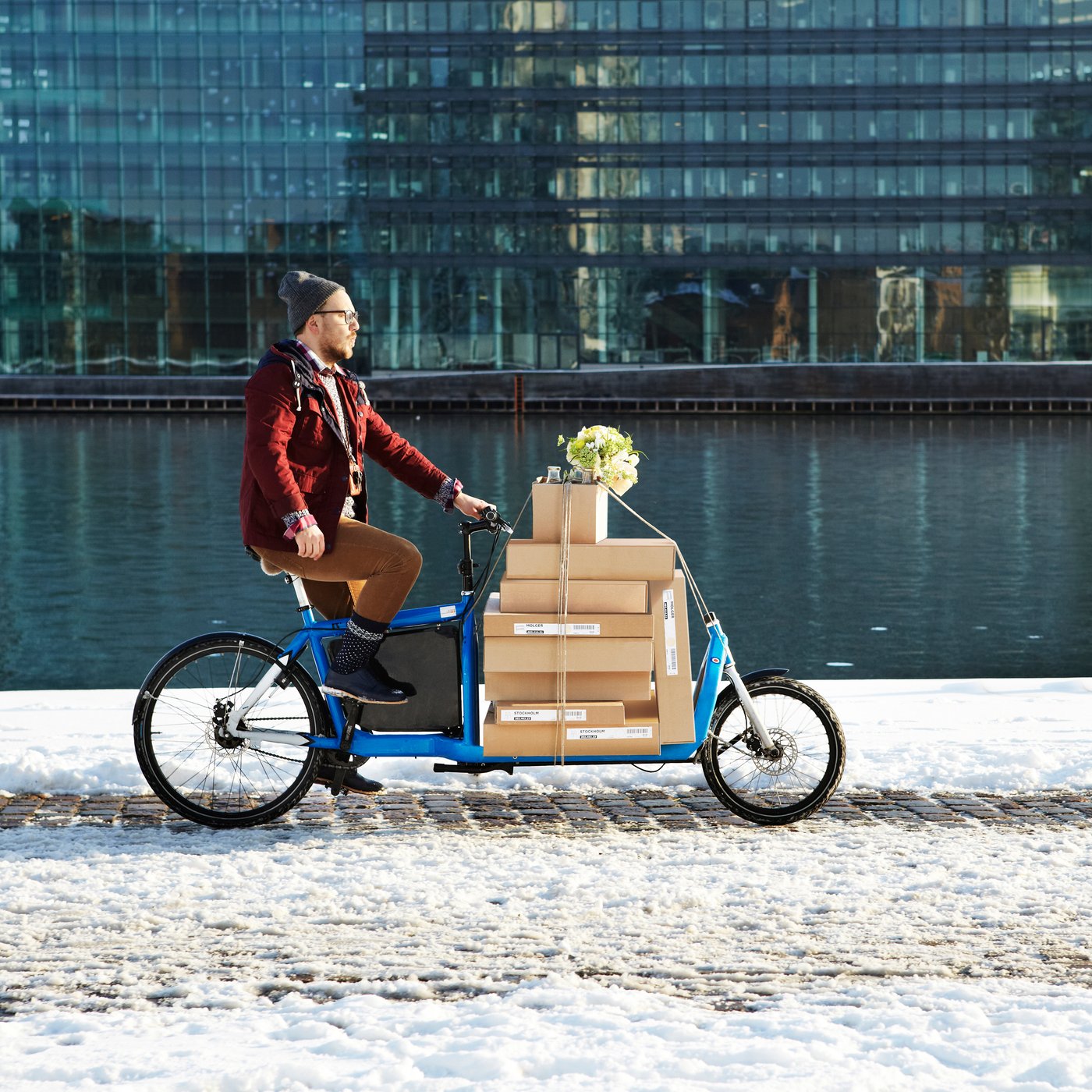 En mand cykler på en ladcykel fyldt med IKEA produkter.
