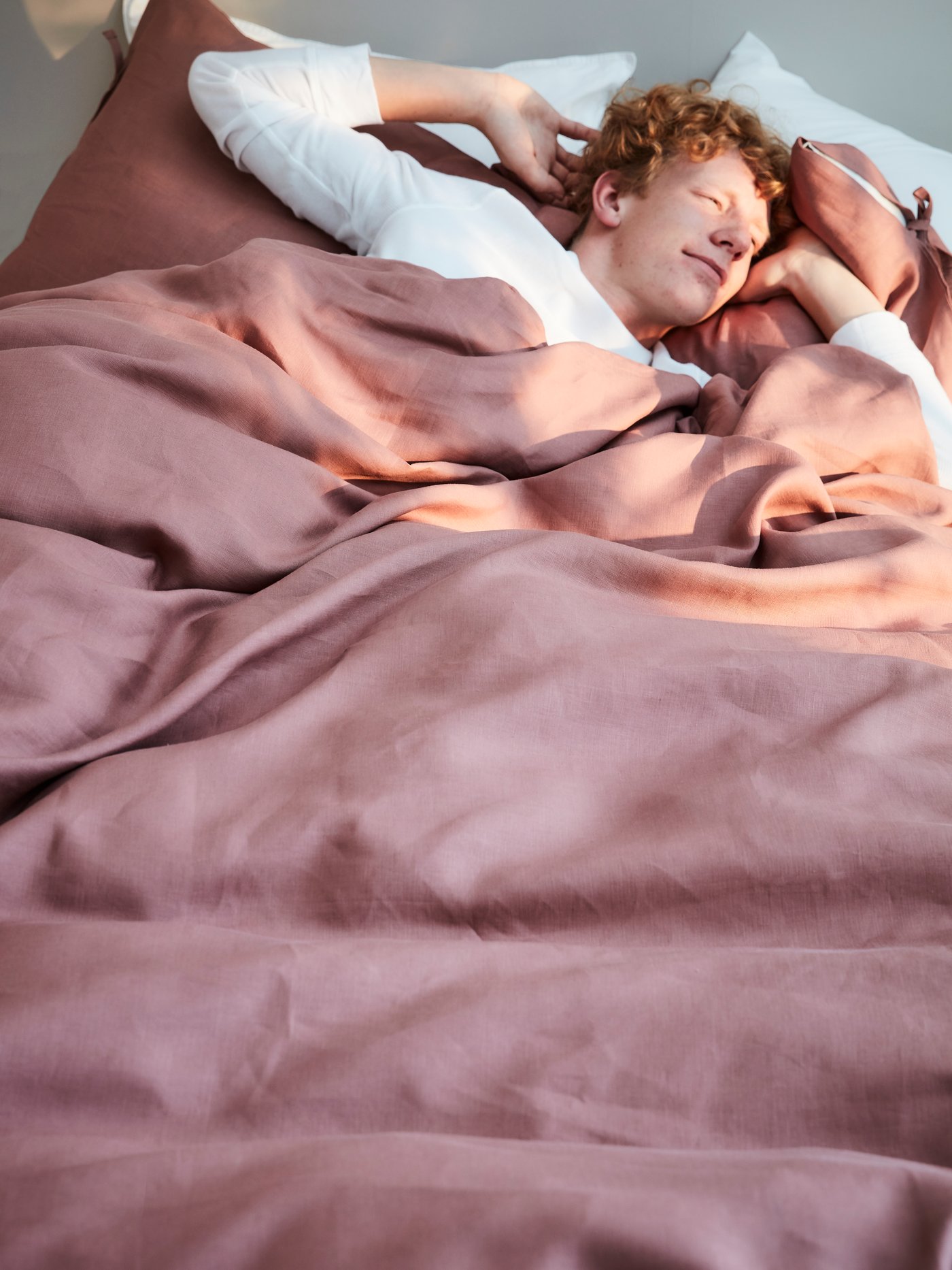 Un uomo mentre sta dormendo avvolto in un copripiumino rosa.