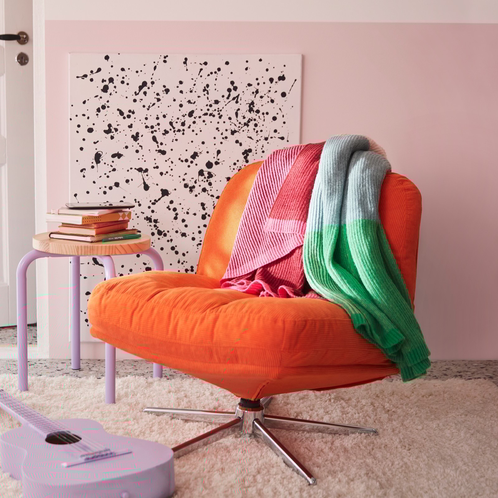 A bedroom features a multicolour MARGOSATRÄD throw placed on a Kelinge orange DYVLINGE swivel easy chair.