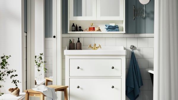 A white HEMNES wash-stand, with a white VÄSTERSJÖN countertop wash-basin, is placed underneath a HEMNES mirror cabinet.