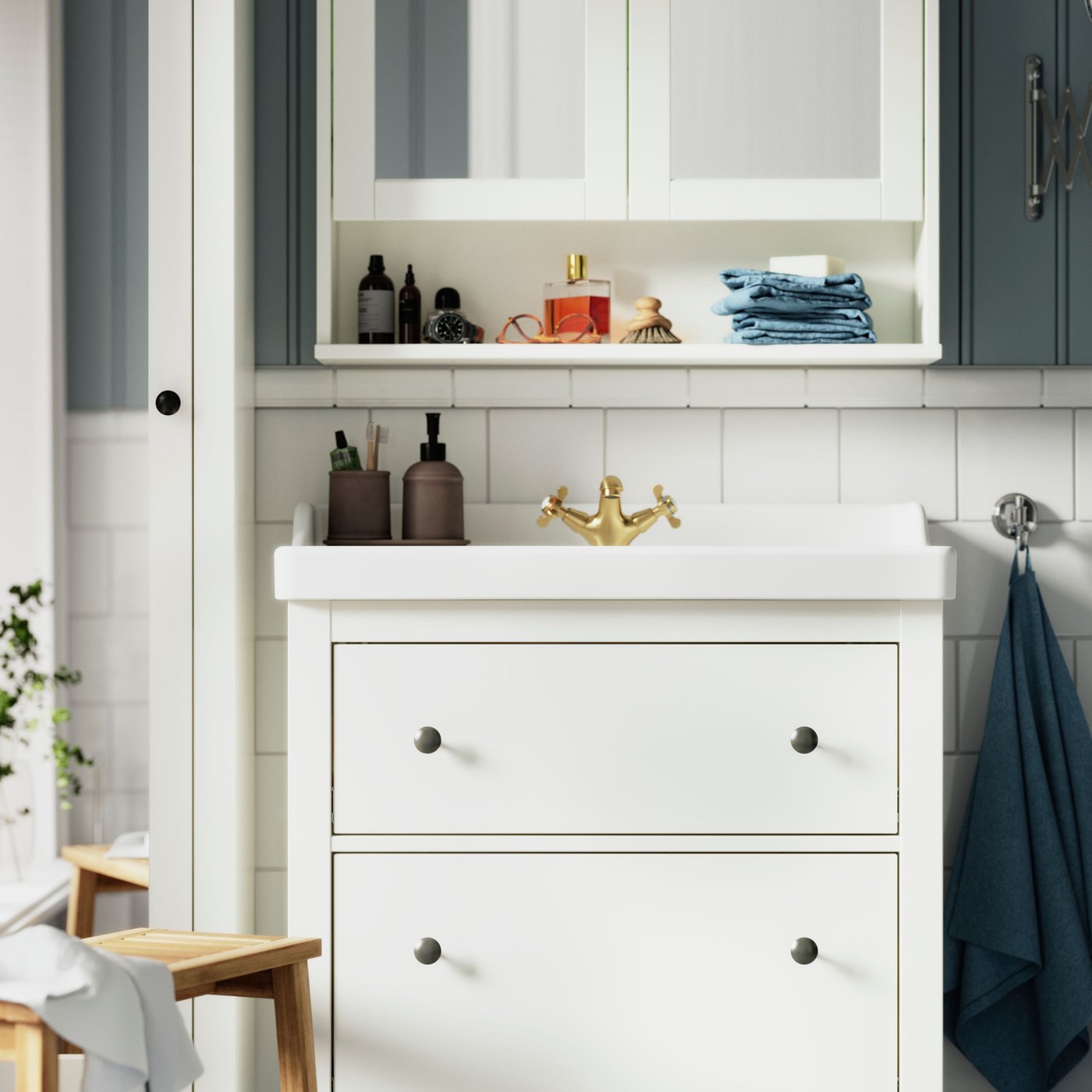 A white HEMNES wash-stand, with a white VÄSTERSJÖN countertop wash-basin, is placed underneath a HEMNES mirror cabinet.