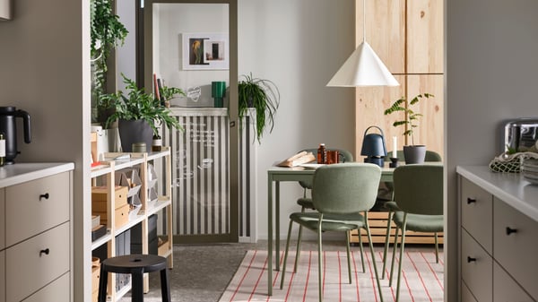 VIHALS chairs stand at a green VIHALS extendable table on a rug underneath a white ZEBRASÄV pendant lamp in a dining room.