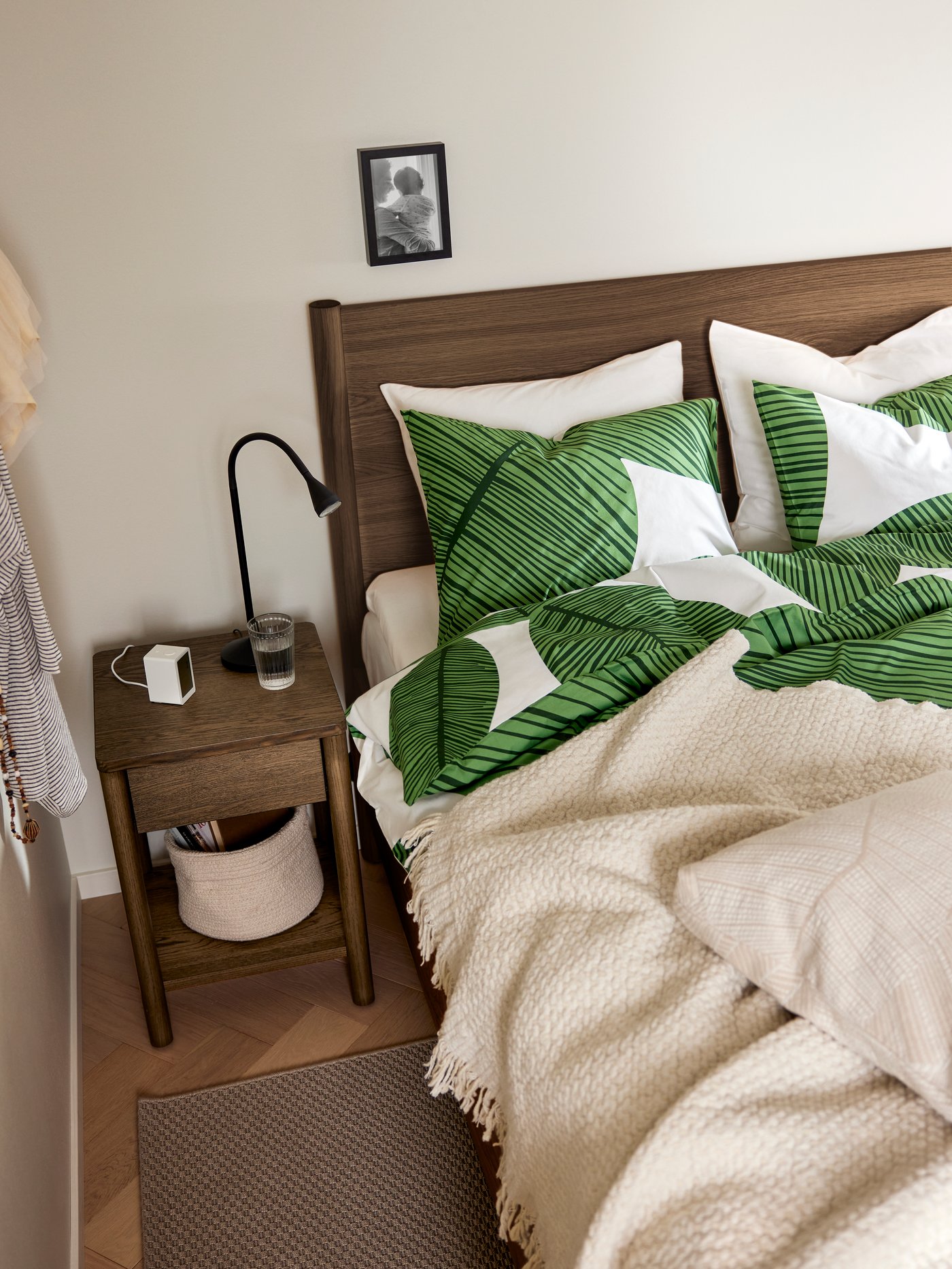 Dormitorio con un marco de cama TONSTAD con almacenamiento colocado junto a una alfombra MORUM tejida plana al aire libre y una mesita de noche TONSTAD.