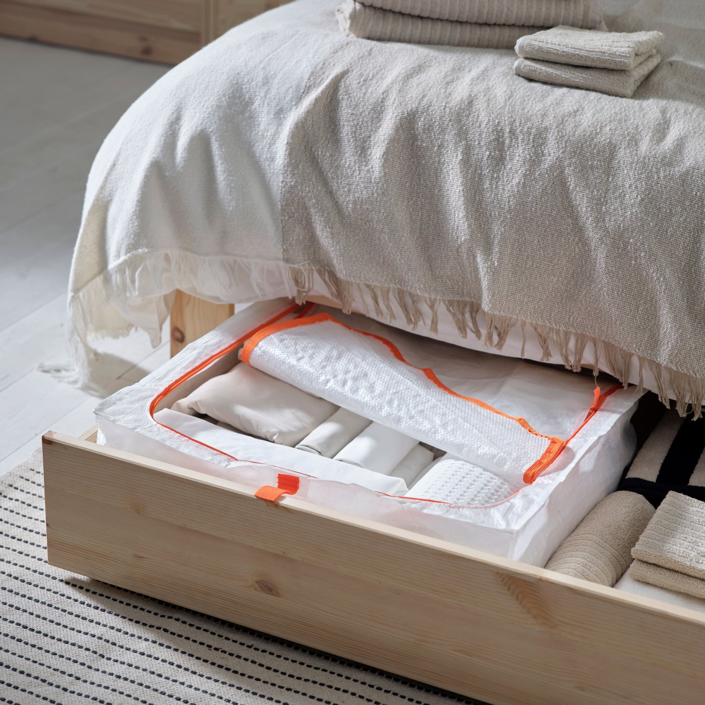 An extended drawer of a GLAMBERGET extendable bed with storage in pine with a PÄRKLA storage case in it.