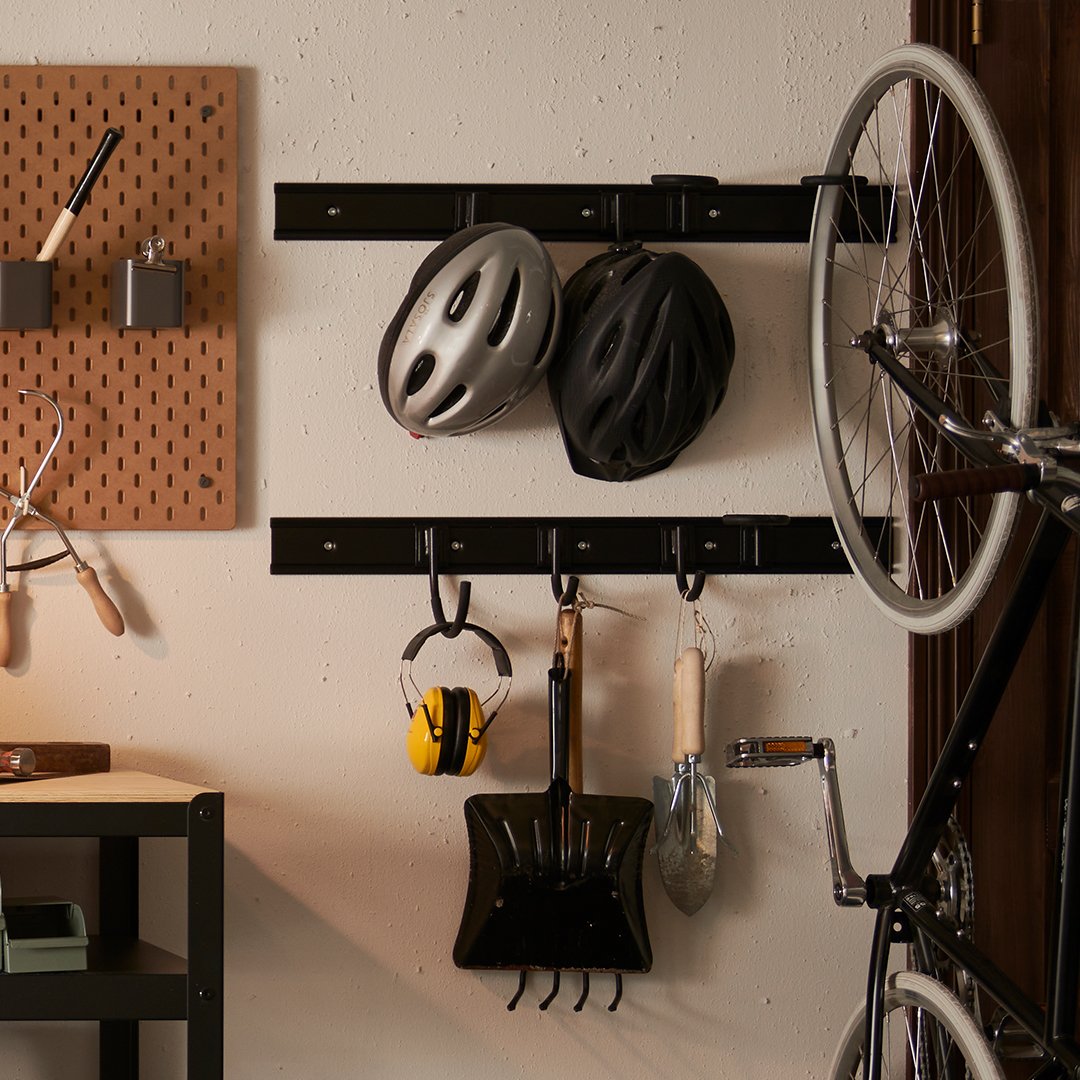 SKADIS pegboard with BRANDUR hooks, helmets and bicycle at the side. 