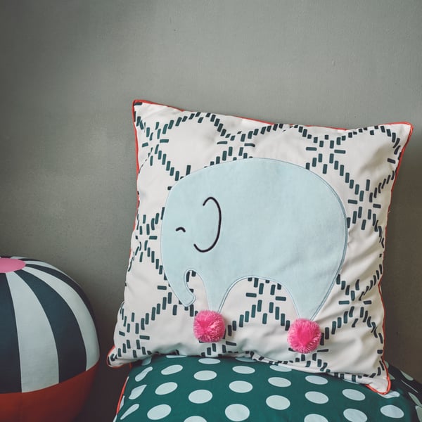 Ein grün-weißes gemustertes Kissen mit einem Elefanten darauf, setzt schöne Boho Akzente in jedem Kinderzimmer.