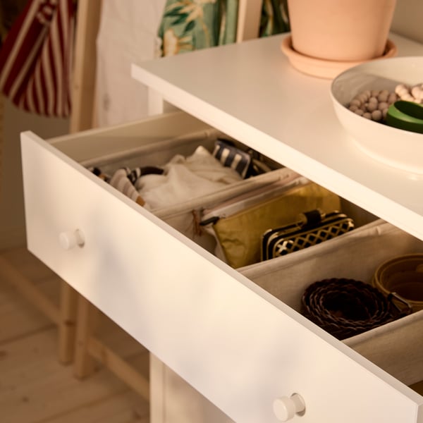 Närbild av en HEMNES byrå med översta lådan utdragen, som visar den prydliga ordningen inuti med PURRPINGLA lådor.