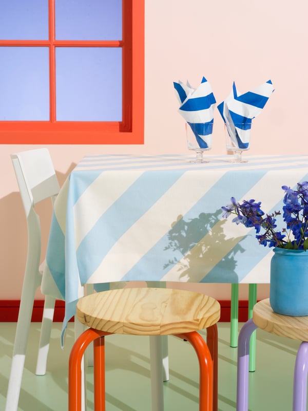 HAVSKATT paper napkins in blue and white stripes are placed in IKEA 365+ clear goblet glasses on a dining table.