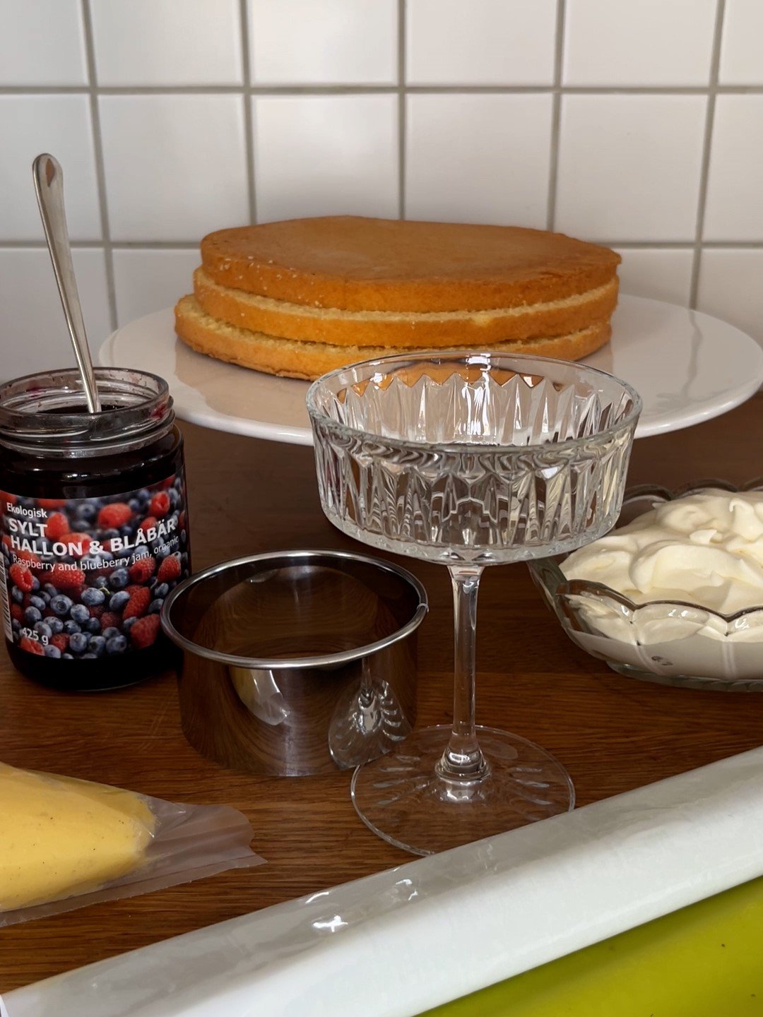 På en köksbänk är ingredienser som redskap till en prinsesstårta i glas upplagt.