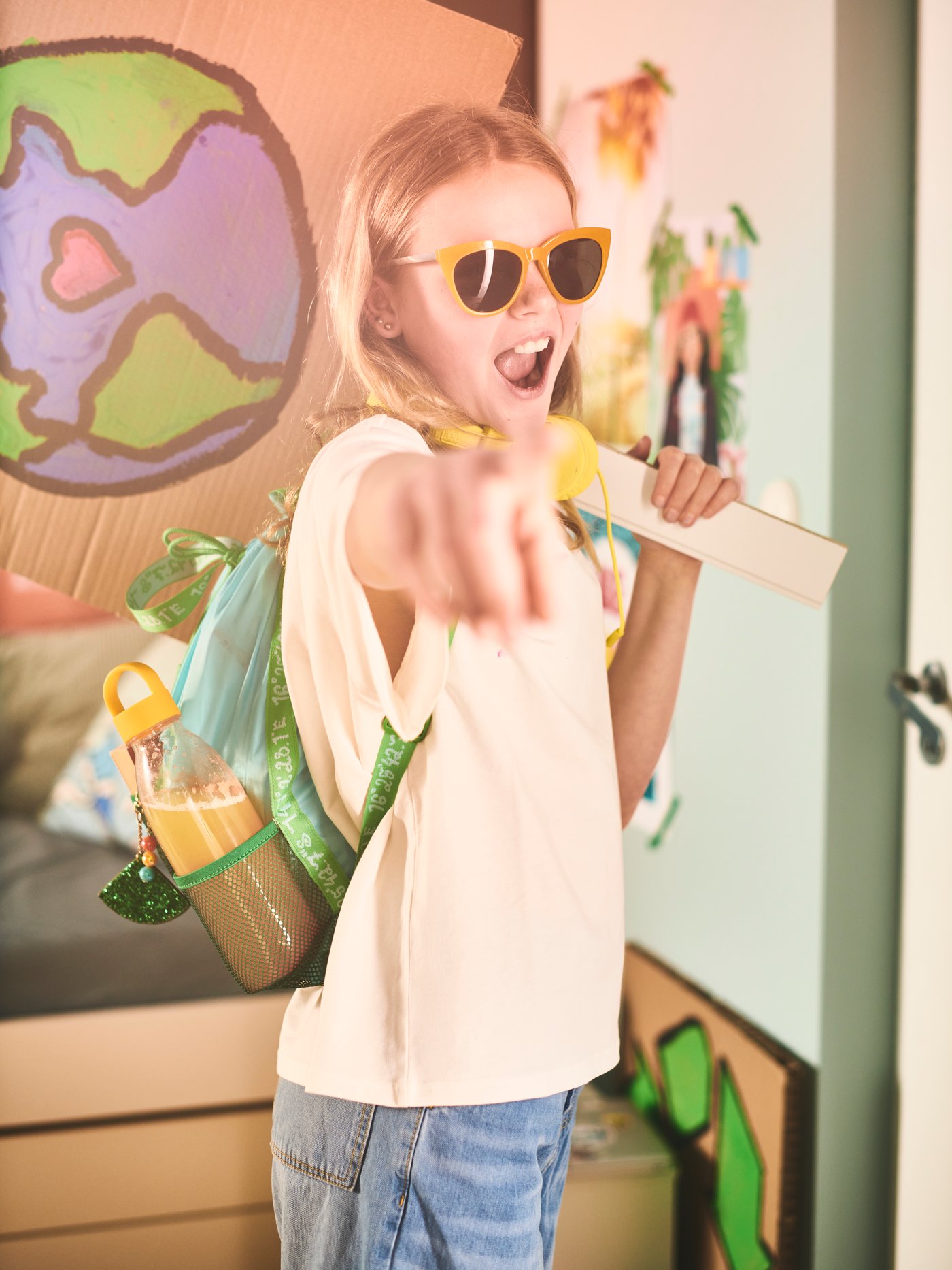Habitación infantil moderna con una persona con una mochila azul de poliéster sosteniendo una botella de agua amarilla.