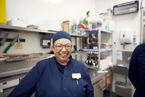 A co-worker smiles in a kitchen of a restaurant.