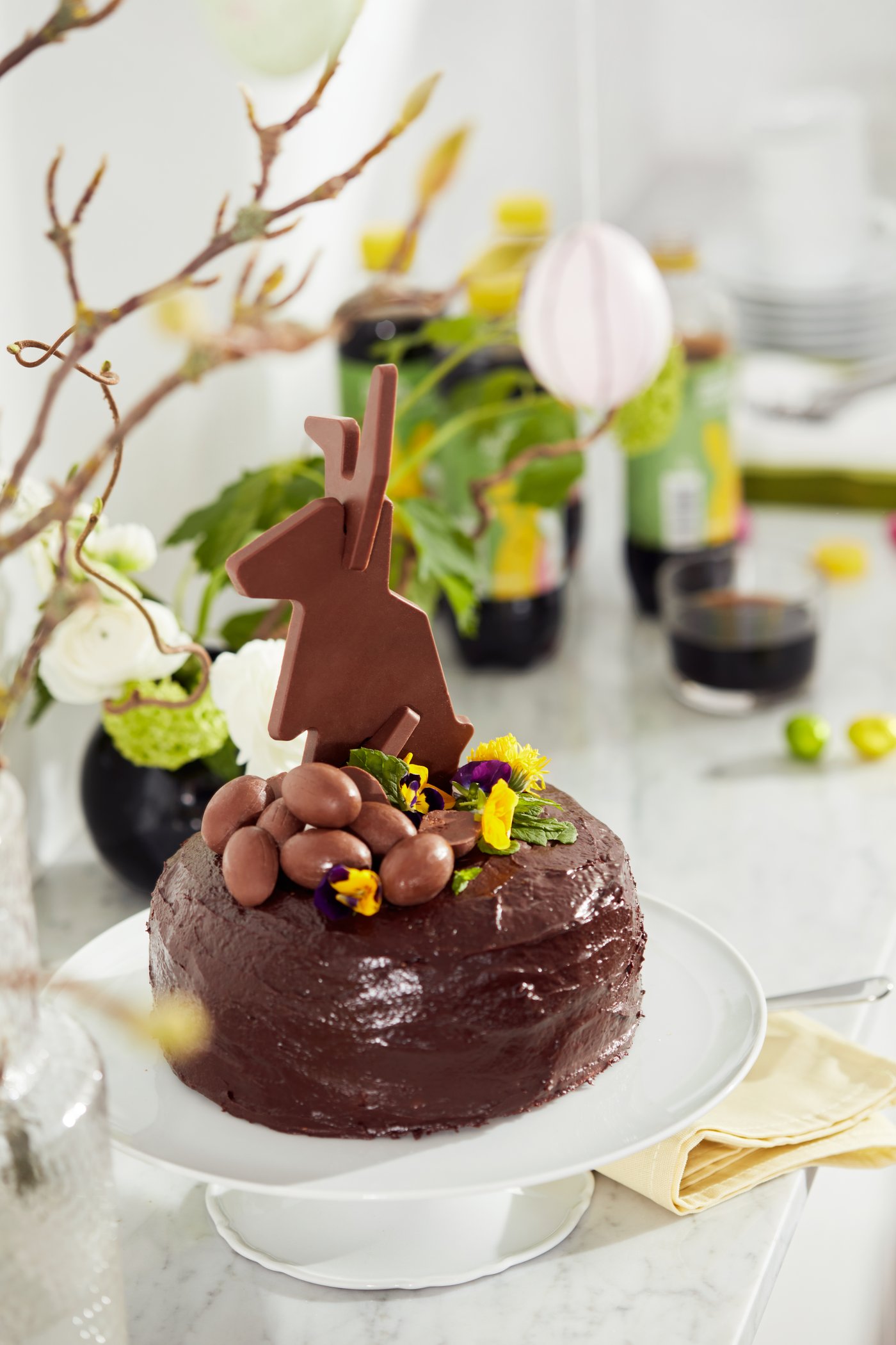 Chocolate cake with VÅRKÄNSLA flat-ack bunny and easter eggs on top on a UPPLAGA cake stand