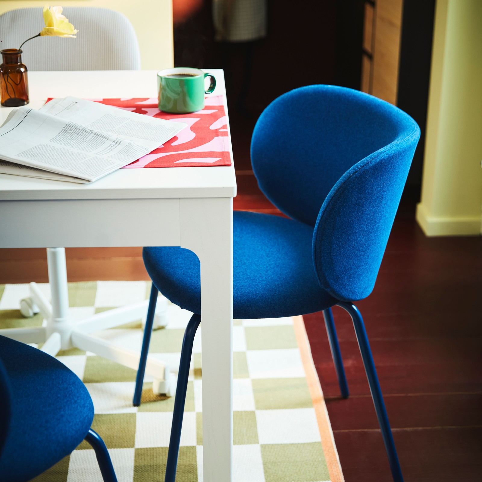 Unha cadeira KRYLBO en Tonerud azul xunto a unha mesa extensible EKEDALEN branca sobre unha alfombra KLASSRUM branca e verde.